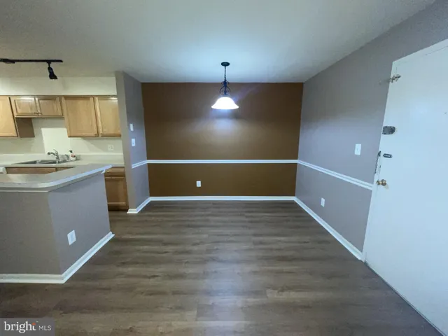 a view of kitchen and empty room with wooden floor