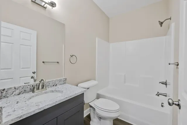a bathroom with a granite countertop sink a toilet and shower
