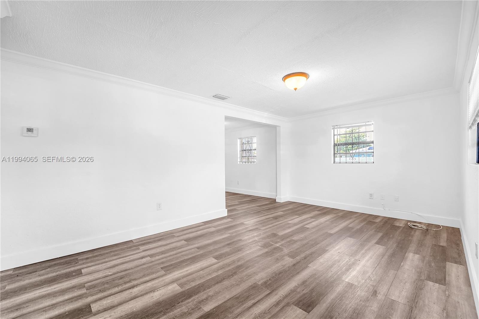 10960 Southwest 219th Street Miami, FL 33170 - Photo 4 of 22 a view of an empty room with wooden floor and windows
