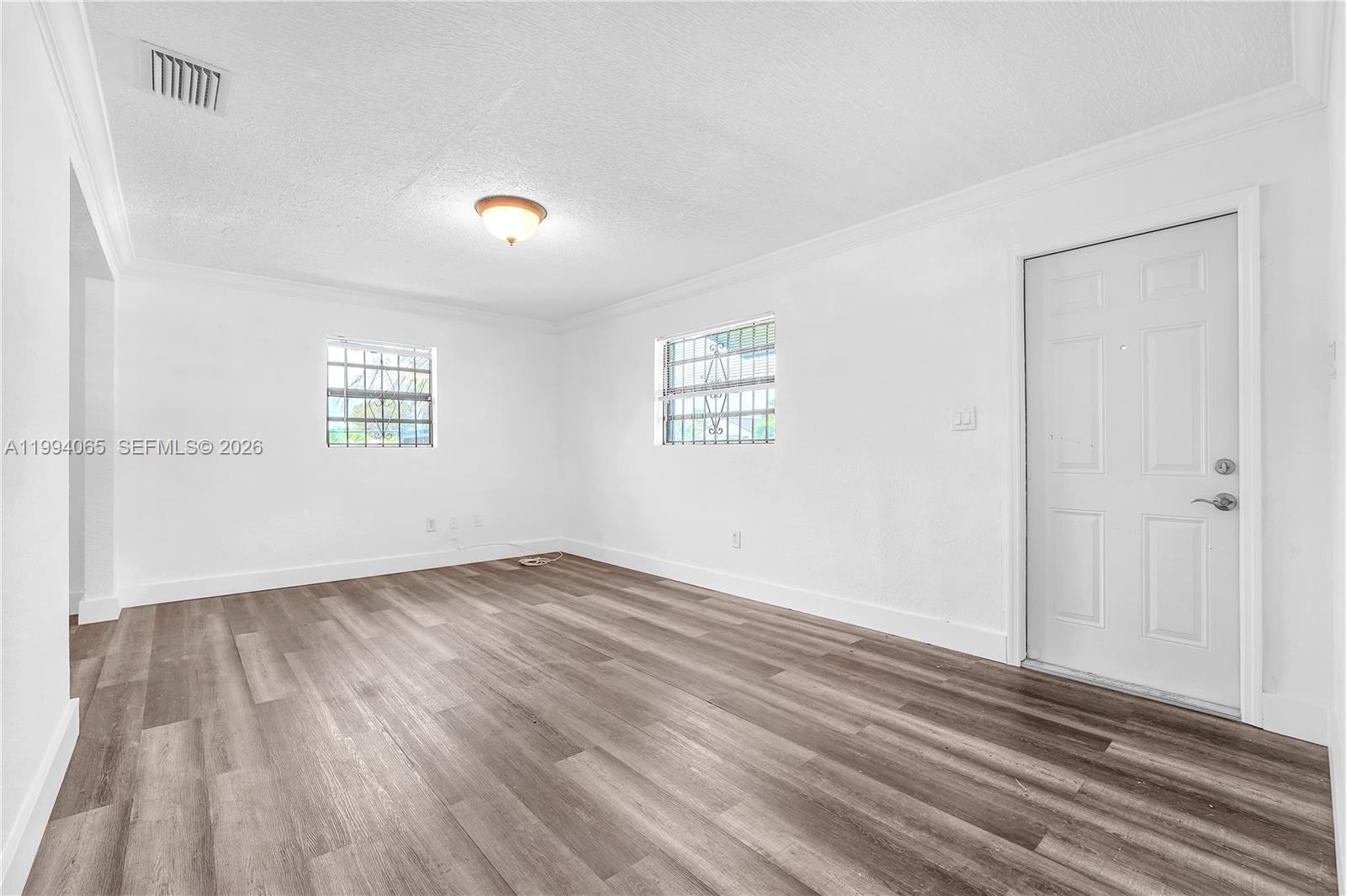 10960 Southwest 219th Street Miami, FL 33170 - Photo 5 of 22 an empty room with wooden floor and windows