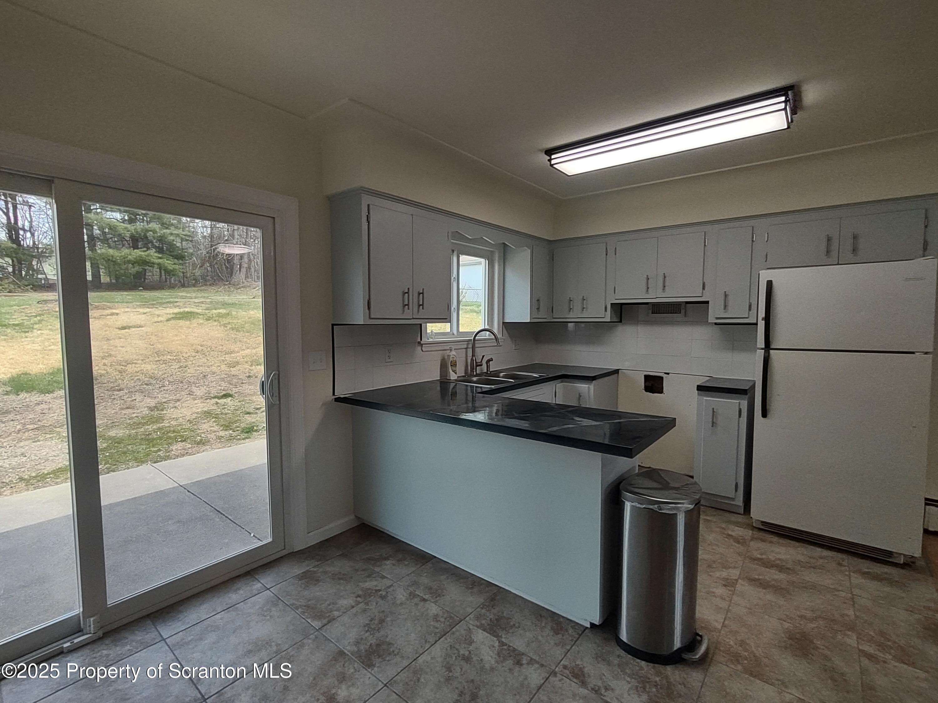 1104 Filbert Street Archbald, PA 18403 - Photo 17 of 39 a kitchen with granite countertop a refrigerator a sink a stove and white cabinets