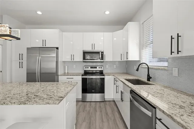 a kitchen with kitchen island granite countertop a sink stove refrigerator and cabinets