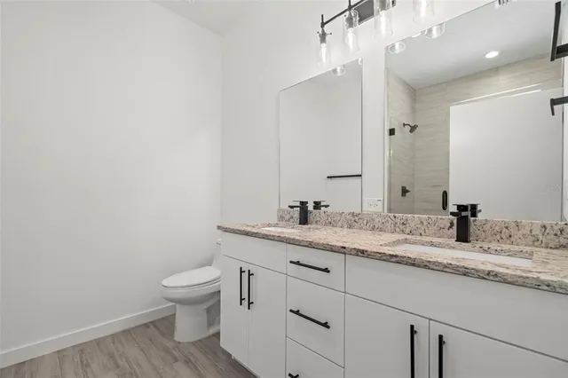 a bathroom with a granite countertop sink mirror vanity and toilet