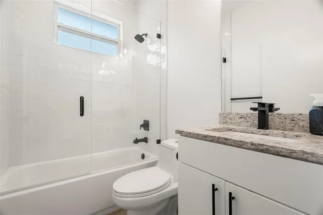 a bathroom with a granite countertop sink a toilet and shower
