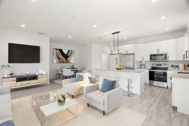 a living room with furniture a flat screen tv and kitchen view