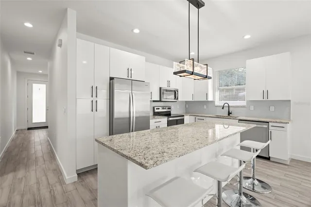 a kitchen with stainless steel appliances granite countertop a kitchen island a stove a refrigerator and a sink