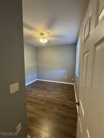 a view of an empty room with chandelier fan and wooden floor