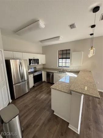 a living room with stainless steel appliances granite countertop furniture wooden floor and a window