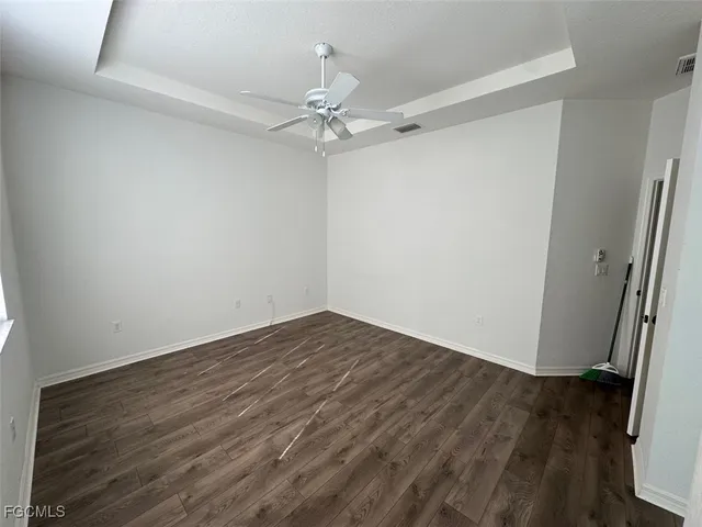 an empty room with wooden floor and fan