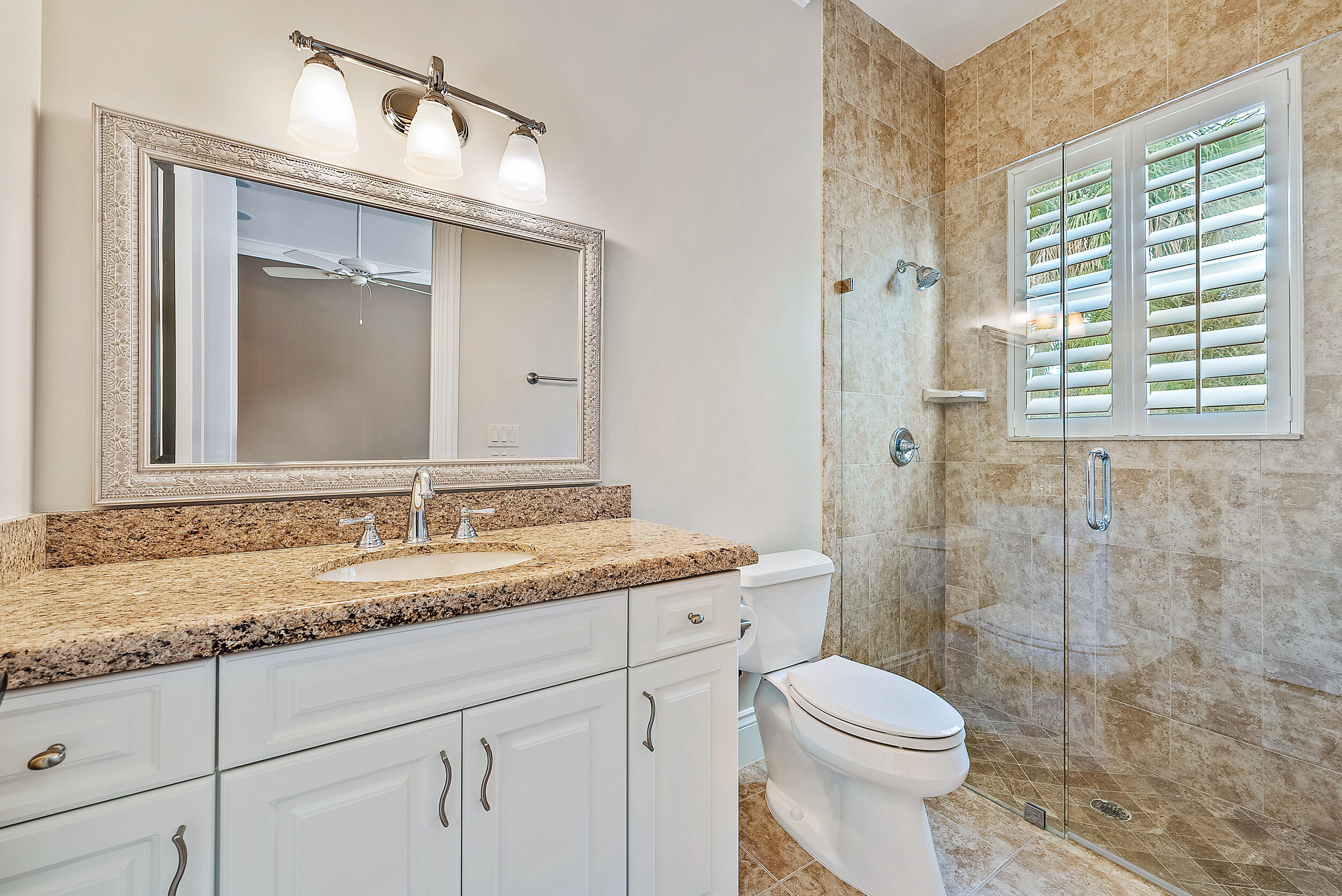 5745 Pennock Point Road Jupiter, FL 33458 - Photo 23 of 31 a bathroom with a granite countertop sink toilet a mirror and shower