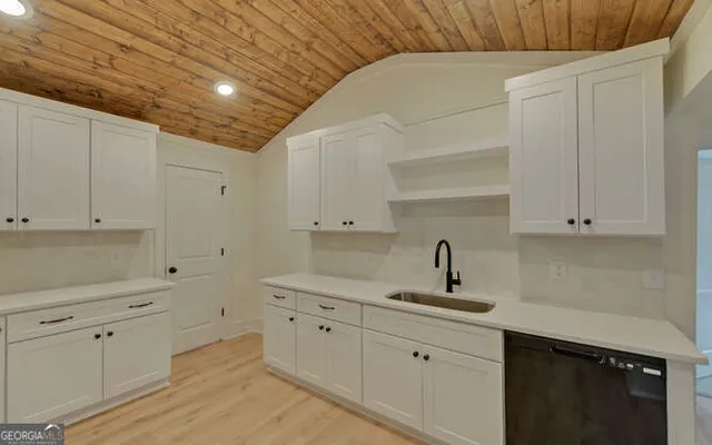 a kitchen with granite countertop a sink stainless steel appliances and white cabinets