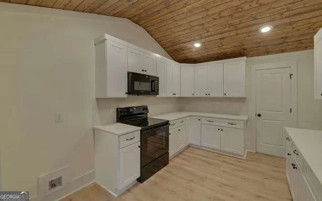a kitchen with granite countertop white cabinets and black appliances