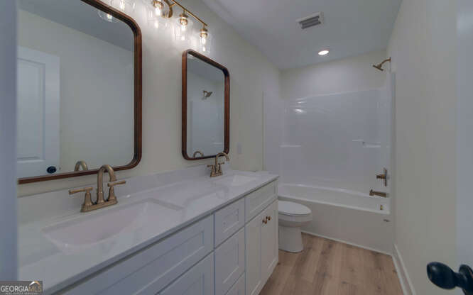 999 East Doyle Street Toccoa, GA 30577 - Photo 20 of 42 a bathroom with a double vanity sink toilet mirror and bathtub