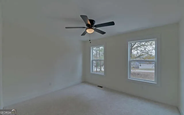 an empty room with a window and a fan