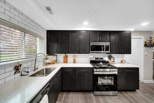 a kitchen with stainless steel appliances a sink dishwasher a stove a microwave a sink and a refrigerator