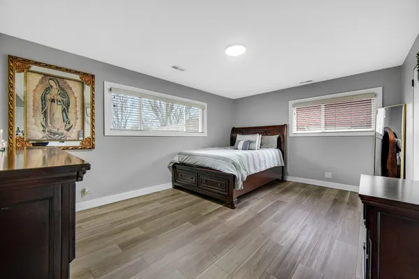 a spacious bedroom with a bed and wooden floor