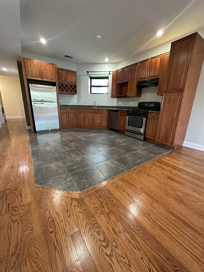 4336 South Indiana Avenue, Unit 1 Chicago, IL 60653 - Photo 4 of 15 a kitchen with stainless steel appliances wooden floor and a refrigerator