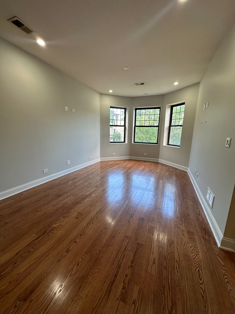 4336 South Indiana Avenue, Unit 1 Chicago, IL 60653 - Photo 5 of 15 an empty room with wooden floor and windows