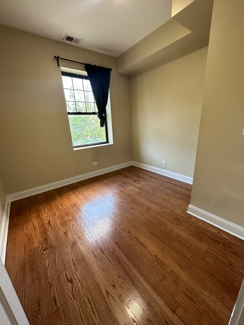 4336 South Indiana Avenue, Unit 1 Chicago, IL 60653 - Photo 9 of 15 an empty room with wooden floor and windows