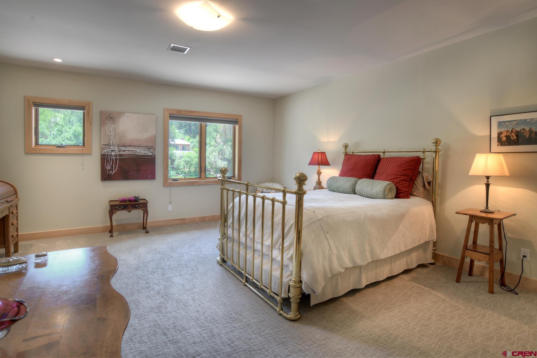 15 Eagle Ridge Road Durango, CO 81301 - Photo 24 of 35 a spacious bedroom with a bed a table and painting