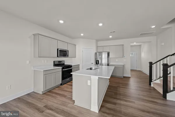 a large kitchen with a center island wooden floor stainless steel appliances and cabinets