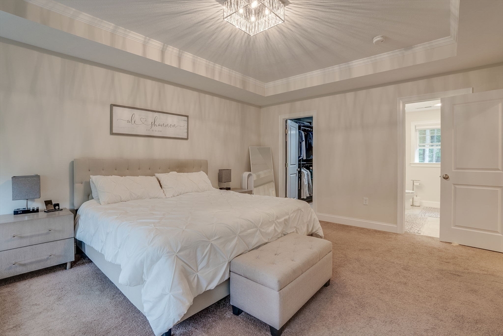 83 Littleton Road Ayer, MA 01432 - Photo 17 of 42 a spacious bedroom with a bed and a chandelier