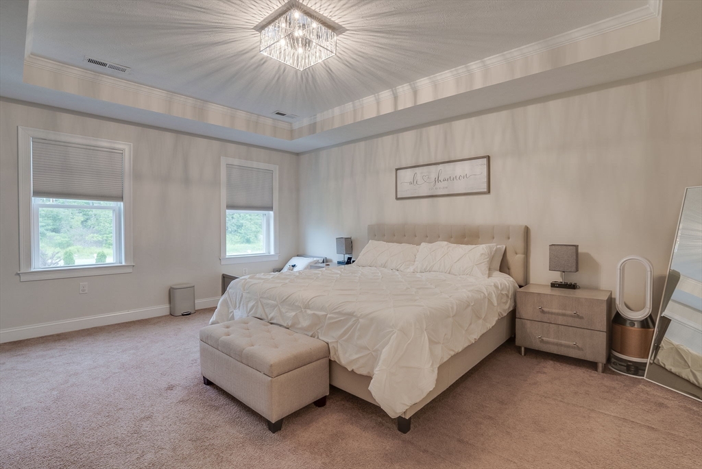 83 Littleton Road Ayer, MA 01432 - Photo 18 of 42 a spacious bedroom with a bed and a chandelier
