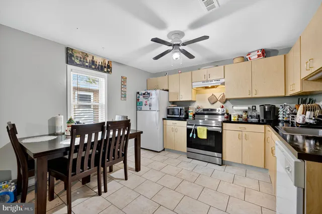 a kitchen with stainless steel appliances granite countertop a stove a sink dishwasher a dining table and chairs with wooden floor