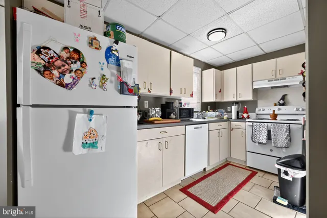 a kitchen with a refrigerator and white cabinets