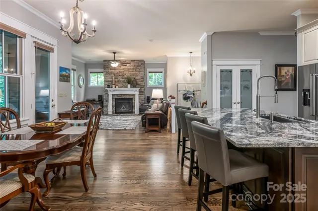 a kitchen with stainless steel appliances granite countertop a dining table chairs refrigerator and sink