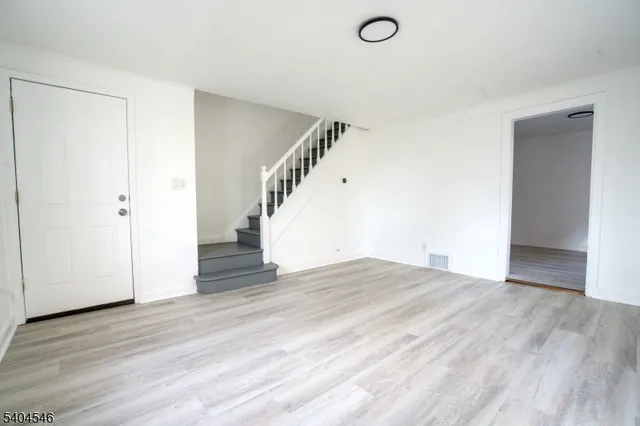 a view of a livingroom with wooden floor and stairs