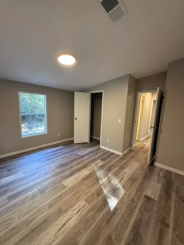 a view of an empty room with wooden floor and a window