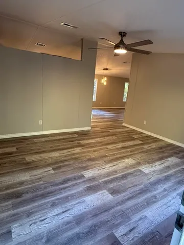a view of a room with wooden floor and a ceiling fan