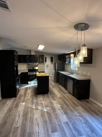 a large kitchen with stainless steel appliances kitchen island granite countertop a large counter top and wooden floors