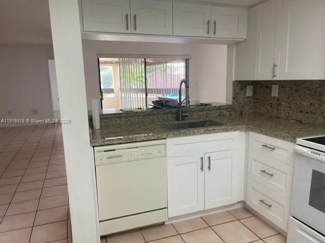 a kitchen with granite countertop white cabinets and white appliances