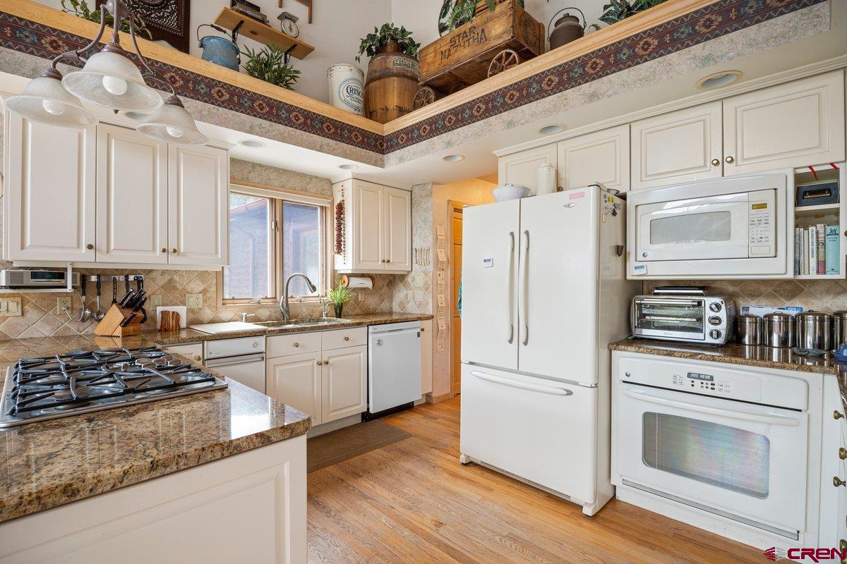 2490 County Road 17 Ridgway, CO 81432 - Photo 17 of 26 a kitchen with stainless steel appliances granite countertop a refrigerator a stove a sink and white cabinets
