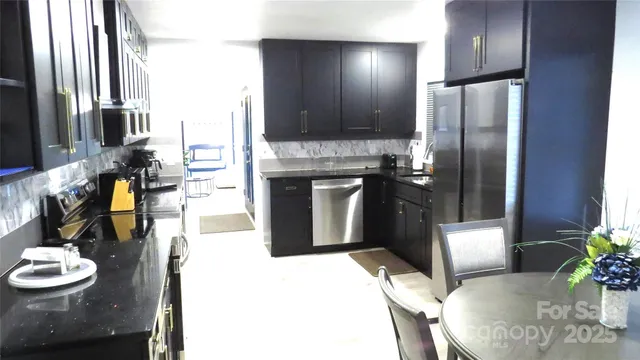 a kitchen with stainless steel appliances kitchen island granite countertop a refrigerator a stove and a sink with wooden floor