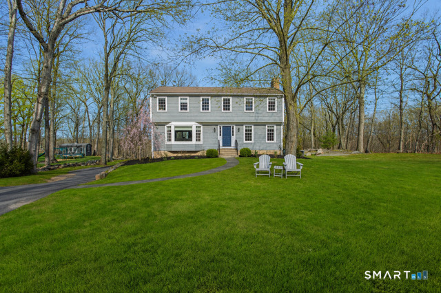 a front view of a house with garden and trees