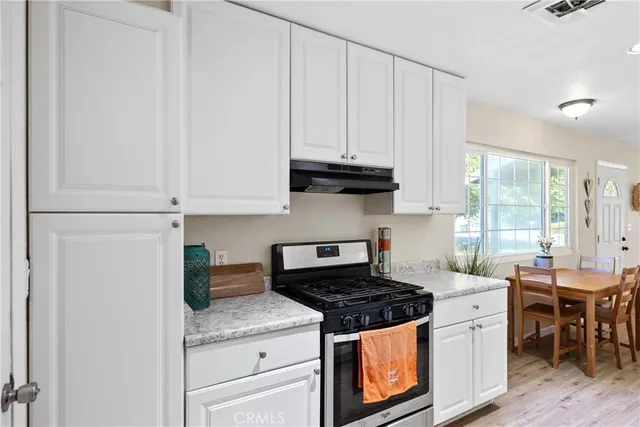 a kitchen with stainless steel appliances granite countertop a stove a sink and a white refrigerator with white cabinets