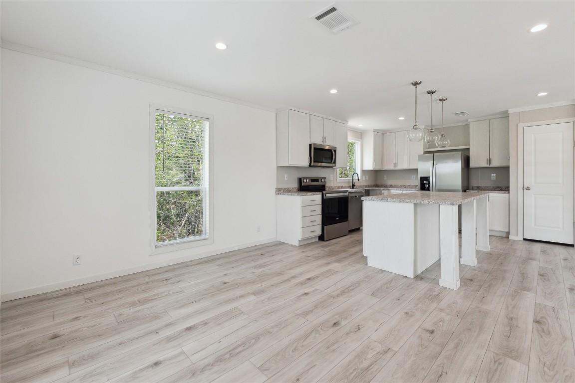 855 Roosevelt Road Kingsbury, TX 78638 - Photo 16 of 33 a kitchen with stainless steel appliances a microwave a stove a sink dishwasher and a refrigerator with wooden floor