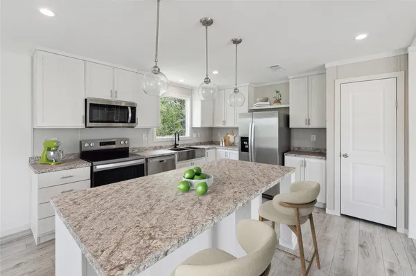a kitchen with stainless steel appliances granite countertop a stove a refrigerator a oven a sink a dining table and chairs