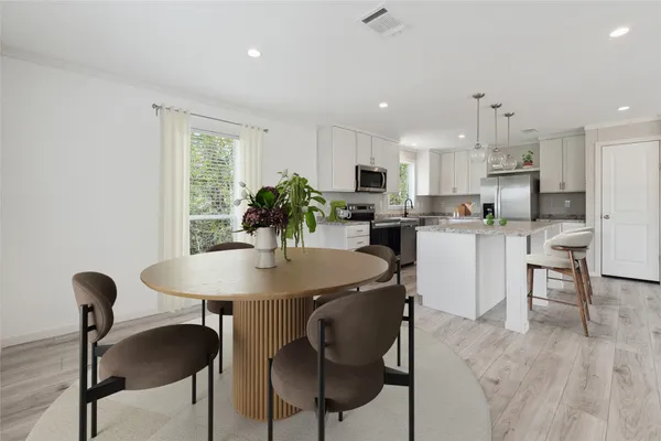 a kitchen with kitchen island a dining table chairs stainless steel appliances and cabinets
