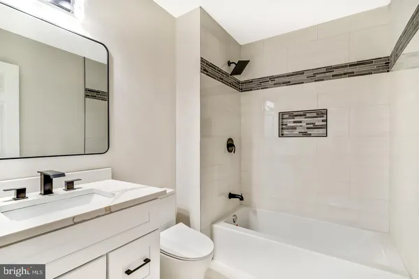 a bathroom with a toilet a sink a tub and mirror