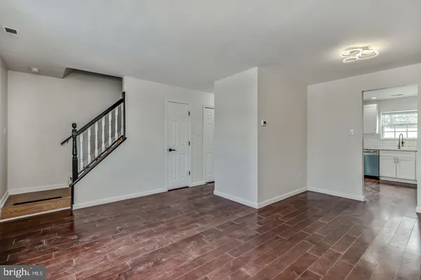 a view of an empty room with wooden floor and stairs