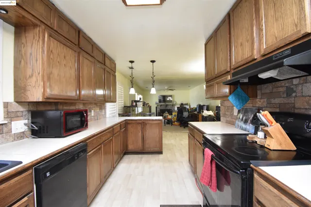 a kitchen with kitchen island granite countertop a sink a stove top oven a counter space and cabinets