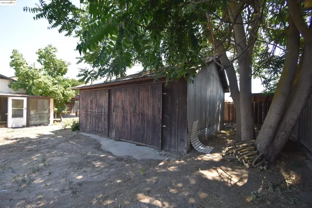 a view of a backyard with large trees and wooden fence