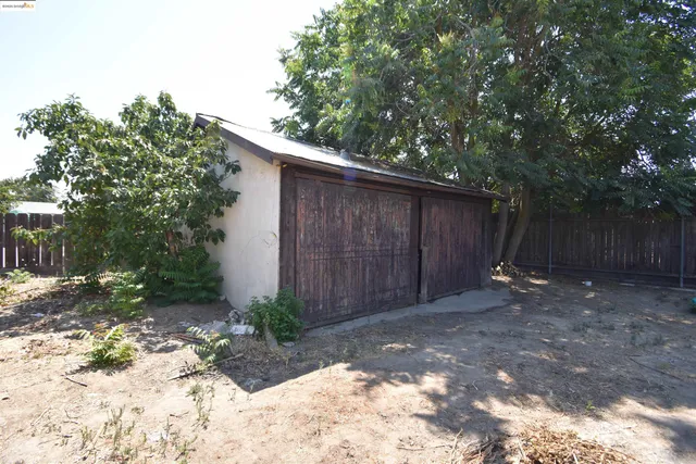 a view of a backyard with large trees and wooden fence