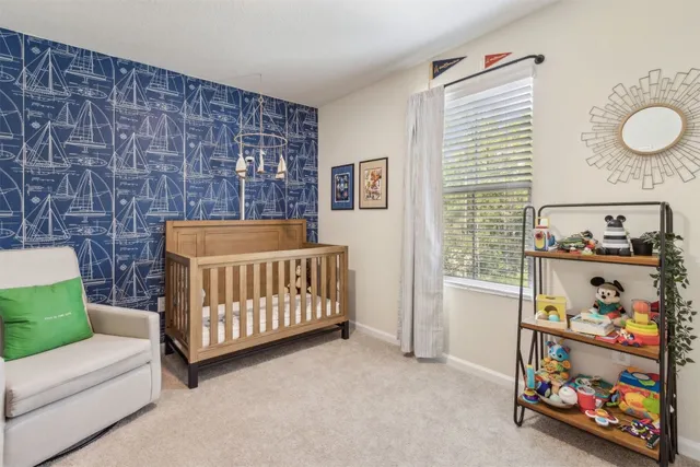 a bedroom with a baby bed a couch and a dresser next to a window