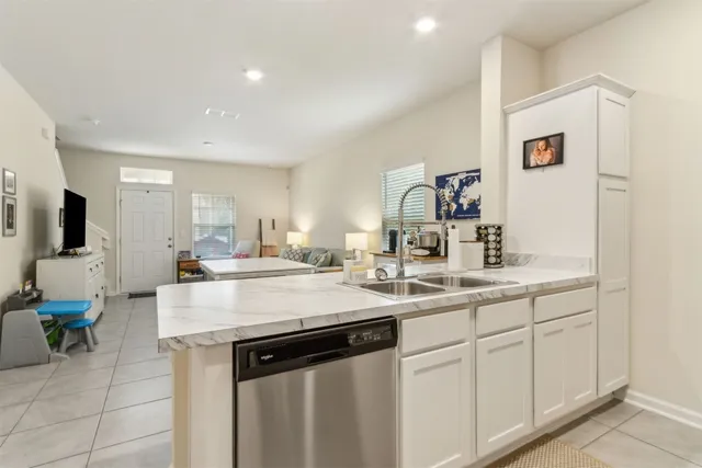 a kitchen with a sink dishwasher and white cabinets with wooden floor