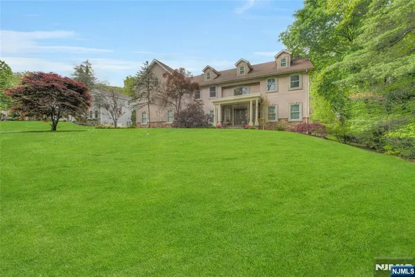 a view of a big house with a big yard and large trees